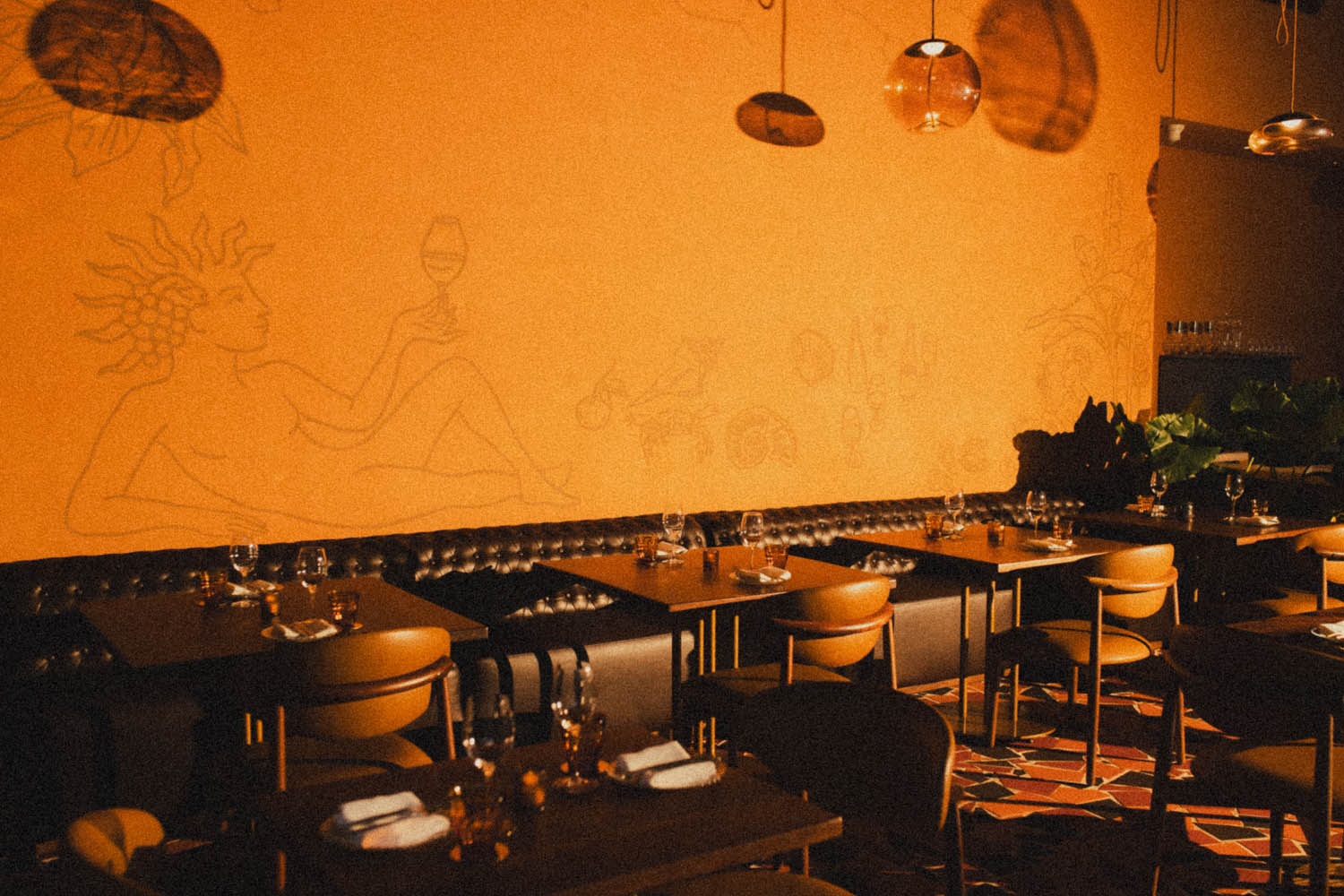 The Chin Chin dining room in warm light, the reclining-figure mural raising a glass above the banquette
